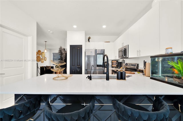 kitchen with kitchen peninsula, decorative light fixtures, white cabinetry, a kitchen breakfast bar, and stainless steel appliances