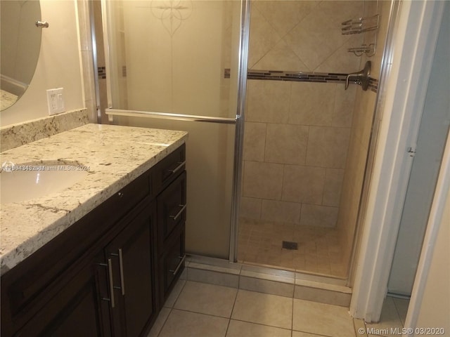 bathroom with tile patterned flooring, vanity, and a shower with door