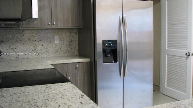 kitchen featuring stainless steel refrigerator with ice dispenser, light stone counters, and tasteful backsplash