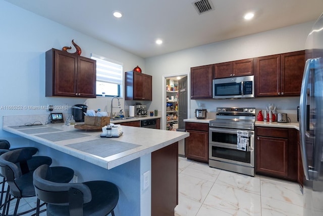 kitchen with stainless steel appliances, kitchen peninsula, a kitchen bar, and sink