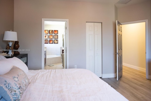 bedroom with light wood-type flooring and connected bathroom