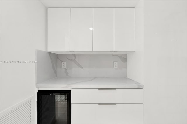 kitchen featuring white cabinetry, light stone countertops, wine cooler, and tasteful backsplash