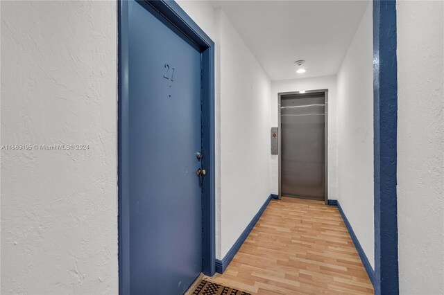 2615 Collins Ave Unit 21, Miami Beach, FL 33140 - hallway with baseboards, elevator, light wood-style flooring, and a textured wall