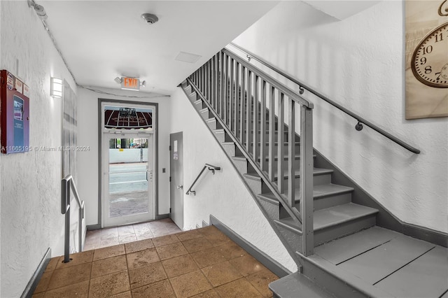2615 Collins Ave Unit 21, Miami Beach, FL 33140 - staircase with baseboards, stone finish flooring, and a textured wall
