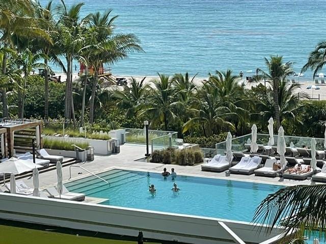 view of swimming pool featuring a water view and a patio area