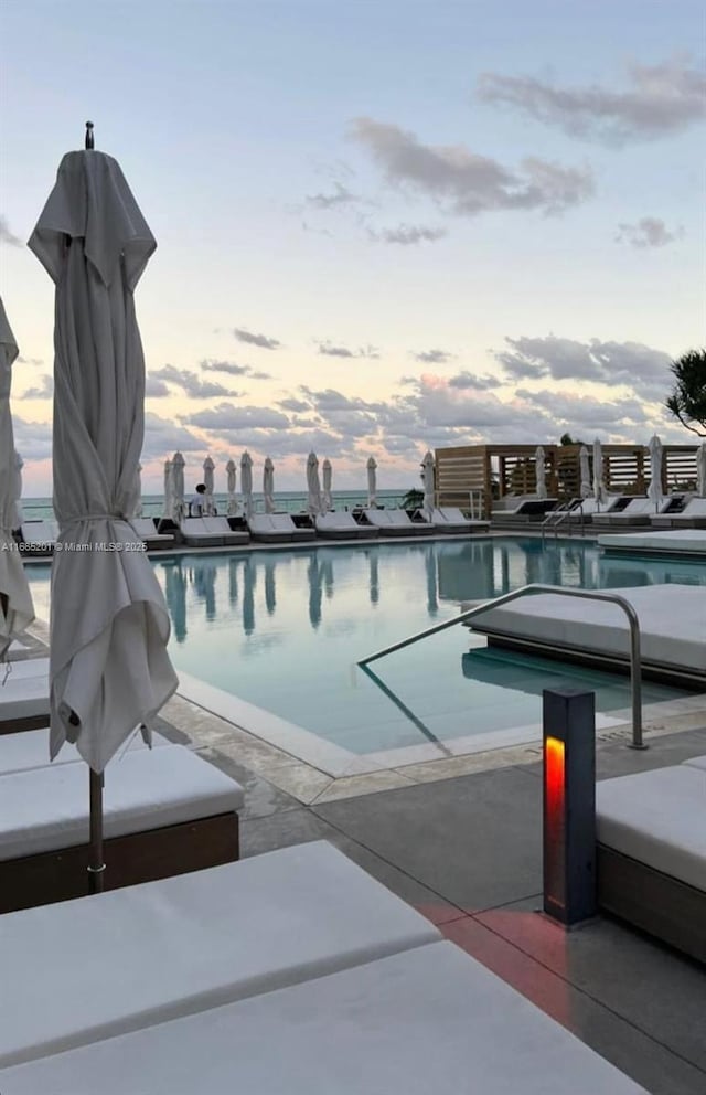 pool at dusk featuring a patio