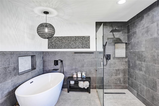 bathroom featuring shower with separate bathtub, tile walls, and tile patterned floors