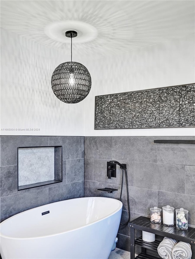 bathroom with tile walls, a tub, and a chandelier