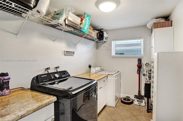 clothes washing area with light tile patterned floors, washer / dryer, and cabinets