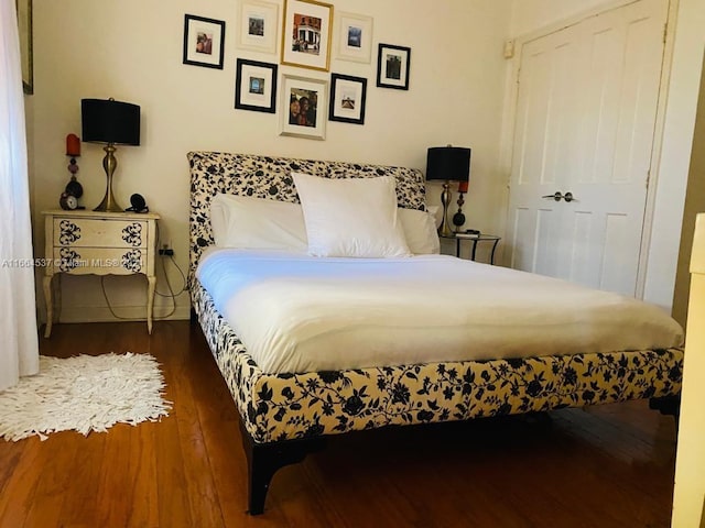 bedroom with dark hardwood / wood-style flooring and a closet