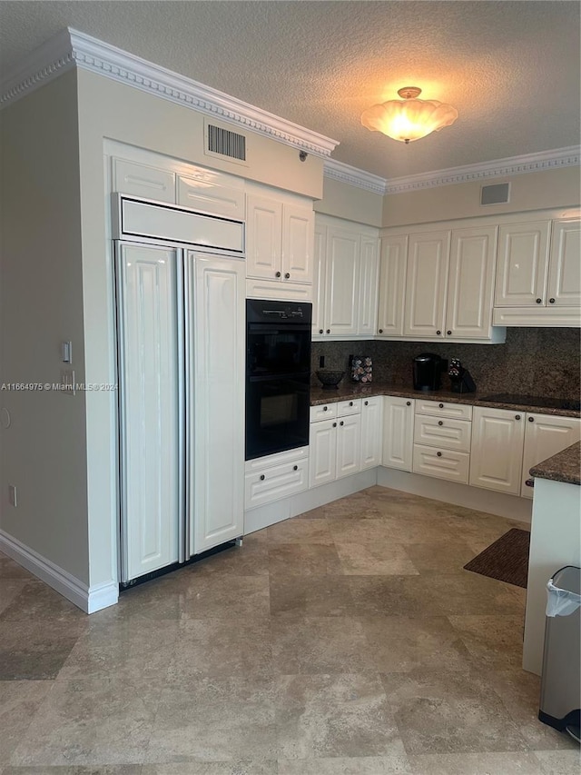 kitchen with white cabinets, paneled built in fridge, black double oven, a textured ceiling, and tasteful backsplash