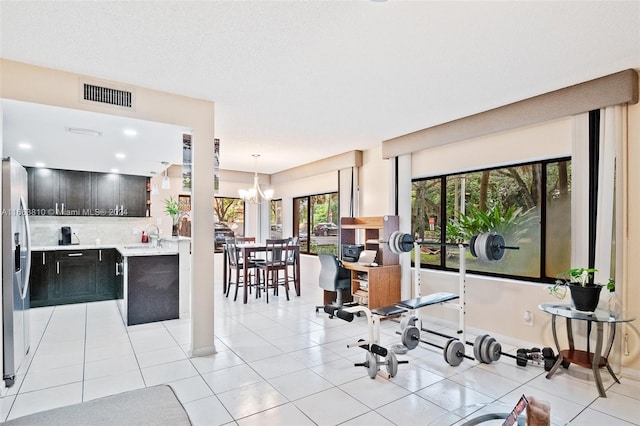 interior space with a notable chandelier, sink, a textured ceiling, and light tile patterned flooring