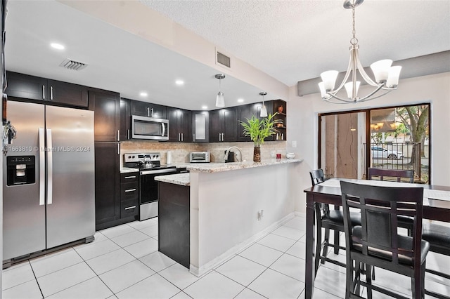 kitchen featuring hanging light fixtures, kitchen peninsula, decorative backsplash, and stainless steel appliances