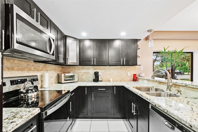 kitchen with light stone counters, tasteful backsplash, sink, appliances with stainless steel finishes, and light tile patterned floors