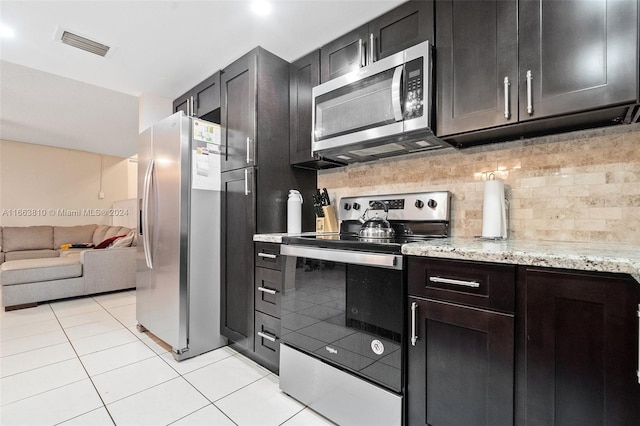 kitchen featuring decorative backsplash, light tile patterned flooring, stainless steel appliances, and light stone counters