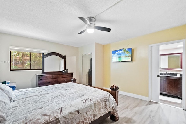 bedroom featuring ceiling fan, a textured ceiling, light hardwood / wood-style flooring, a closet, and ensuite bath