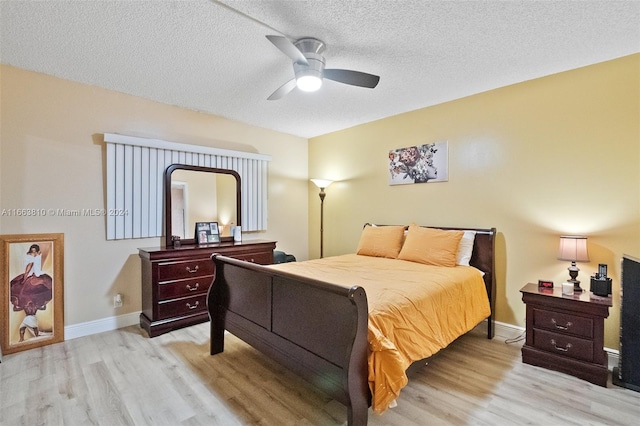 bedroom featuring light wood-type flooring, ceiling fan, and a textured ceiling