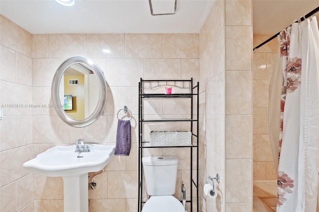 bathroom featuring a shower with shower curtain, tile walls, and toilet