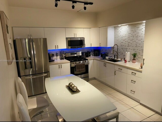 kitchen featuring sink, backsplash, stainless steel appliances, white cabinets, and light tile patterned floors