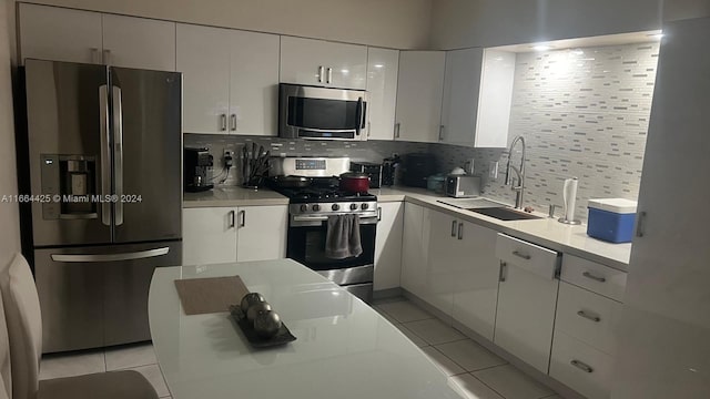 kitchen featuring stainless steel appliances, sink, light tile patterned floors, white cabinets, and tasteful backsplash