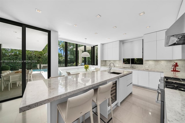 5327 N Bay Rd, Miami Beach, FL 33140 - kitchen with modern cabinets, a sink, wall chimney exhaust hood, decorative backsplash, and floor to ceiling windows