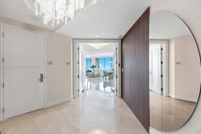 hall featuring arched walkways, baseboards, and a notable chandelier