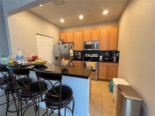 kitchen with a breakfast bar area, light tile patterned floors, and stainless steel appliances