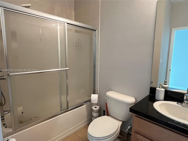 full bathroom featuring combined bath / shower with glass door, vanity, toilet, and tile patterned floors