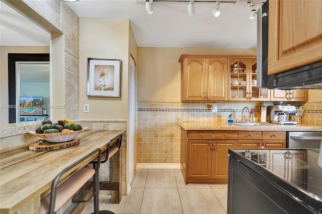 kitchen with light tile patterned floors, electric range, glass insert cabinets, light countertops, and stainless steel dishwasher