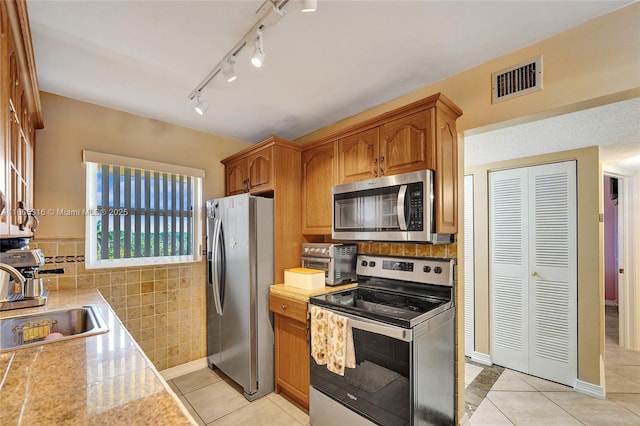 kitchen featuring stainless steel appliances, visible vents, a sink, and light tile patterned floors