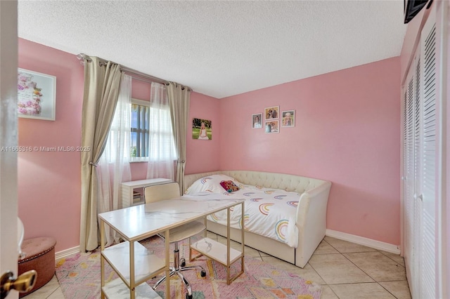 bedroom featuring baseboards, a textured ceiling, and light tile patterned flooring