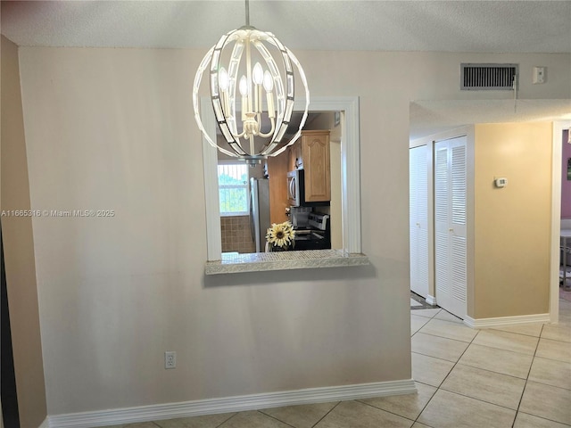 unfurnished dining area featuring light tile patterned floors, a textured ceiling, and an inviting chandelier