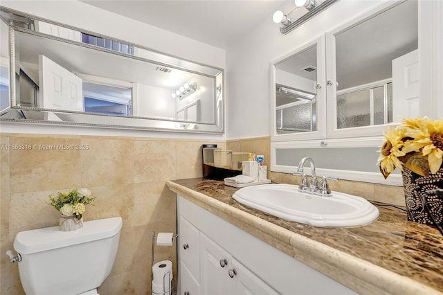 bathroom with toilet, visible vents, tile walls, and vanity