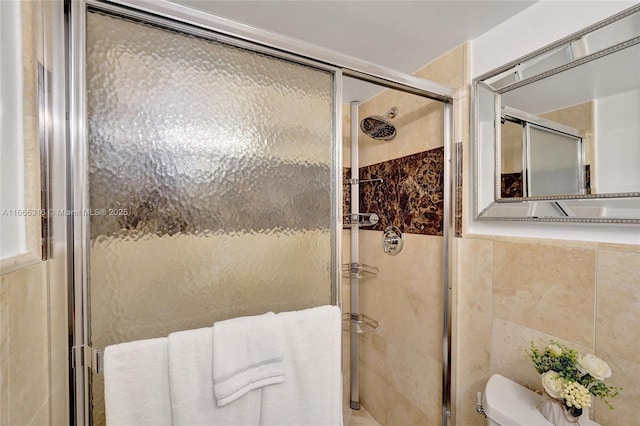 full bathroom with a stall shower, toilet, and tile walls