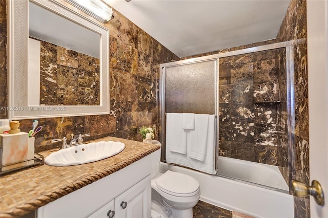 full bath featuring shower / bath combination with glass door, tile walls, tasteful backsplash, toilet, and vanity