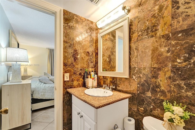 half bath featuring tile patterned flooring, toilet, vanity, tile walls, and ensuite bath