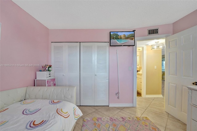 unfurnished bedroom with light tile patterned floors, a textured ceiling, visible vents, baseboards, and a closet