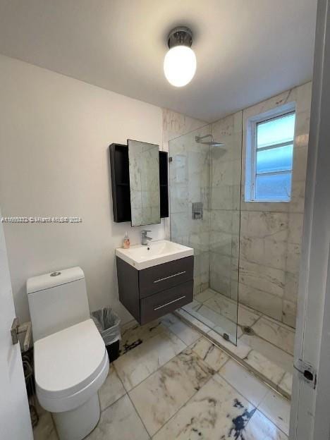 bathroom featuring a tile shower, vanity, and toilet