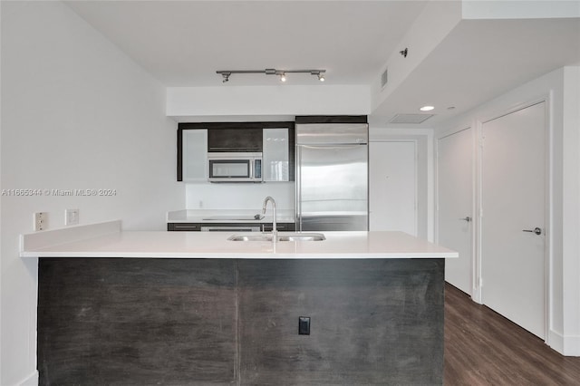 kitchen with stainless steel appliances, kitchen peninsula, dark wood-type flooring, and sink