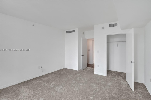 unfurnished bedroom featuring light colored carpet and a closet