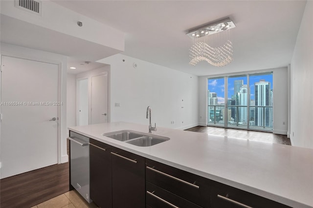 kitchen with pendant lighting, sink, stainless steel dishwasher, a wall of windows, and light hardwood / wood-style floors