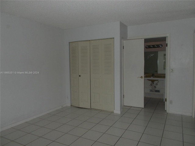 unfurnished bedroom featuring a closet, light tile patterned flooring, and a textured ceiling