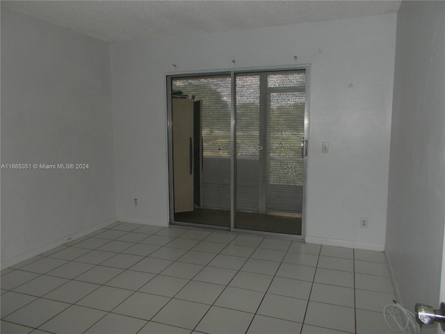 tiled empty room featuring a textured ceiling