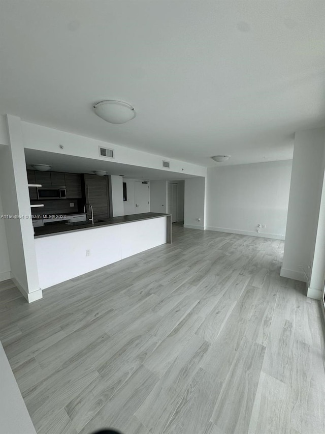 unfurnished living room with light wood-type flooring and sink