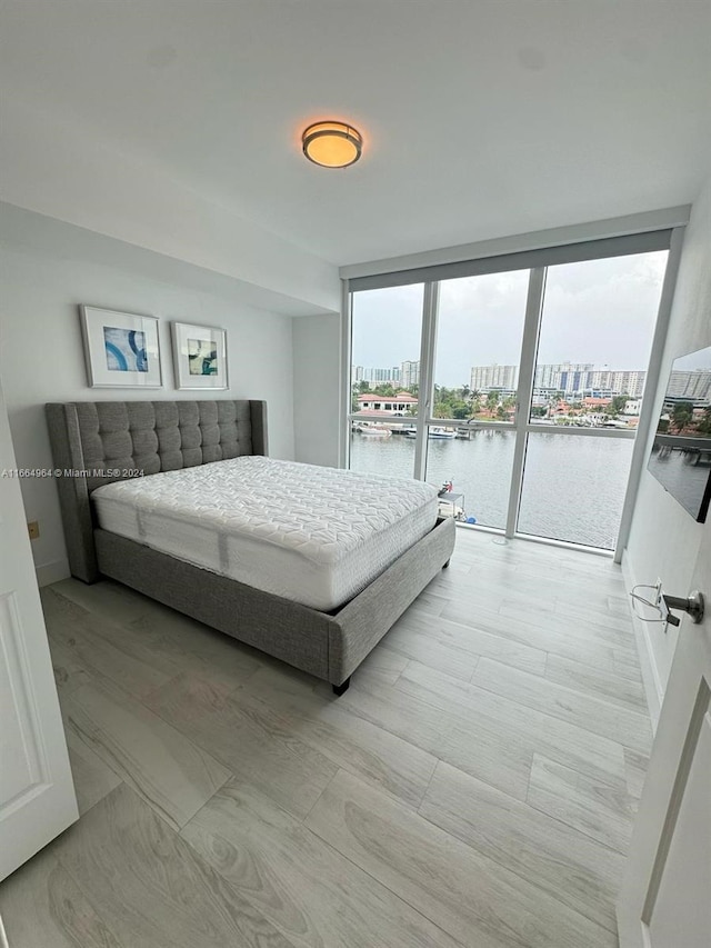 bedroom with a water view, multiple windows, a wall of windows, and access to outside