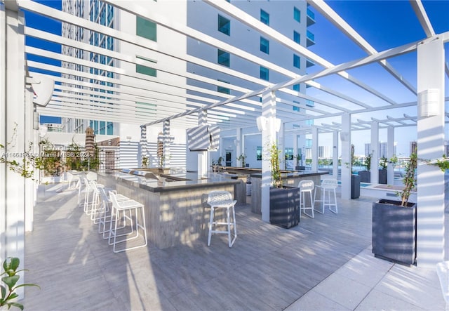 deck featuring an outdoor bar and a pergola