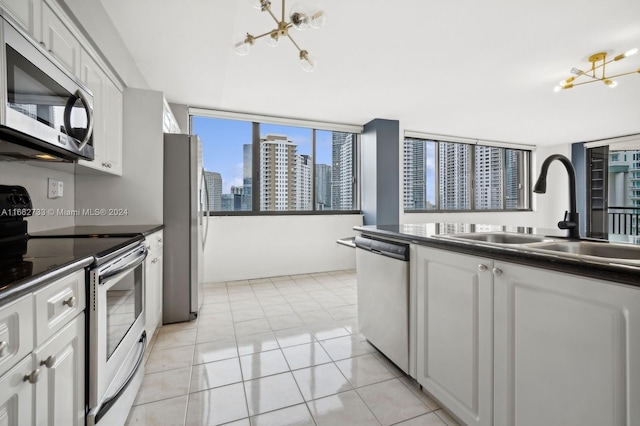 kitchen featuring appliances with stainless steel finishes, white cabinetry, sink, and a notable chandelier