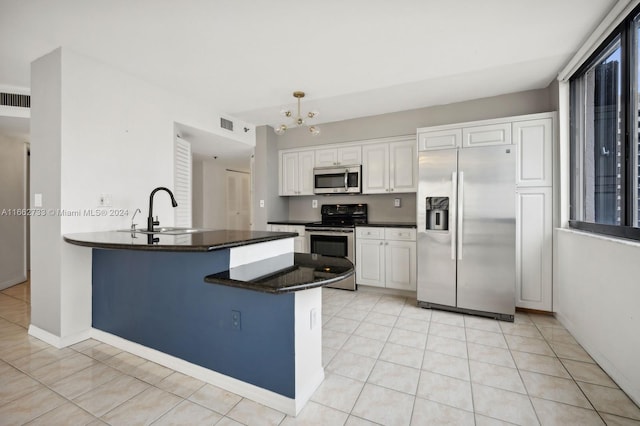 kitchen with white cabinets, sink, kitchen peninsula, appliances with stainless steel finishes, and a notable chandelier