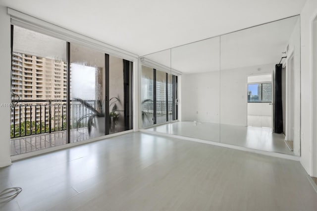 spare room with hardwood / wood-style flooring and a wall of windows