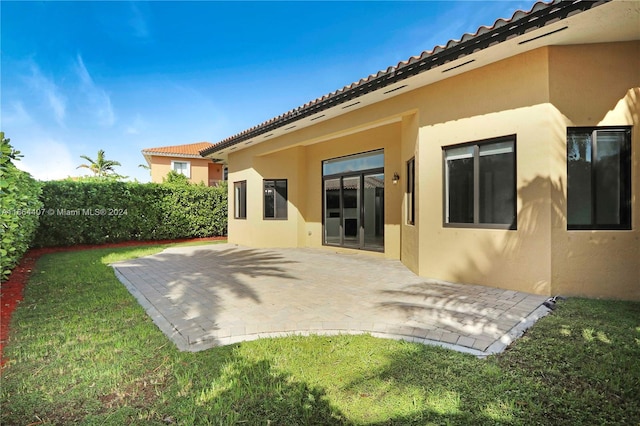 back of house with a lawn and a patio area